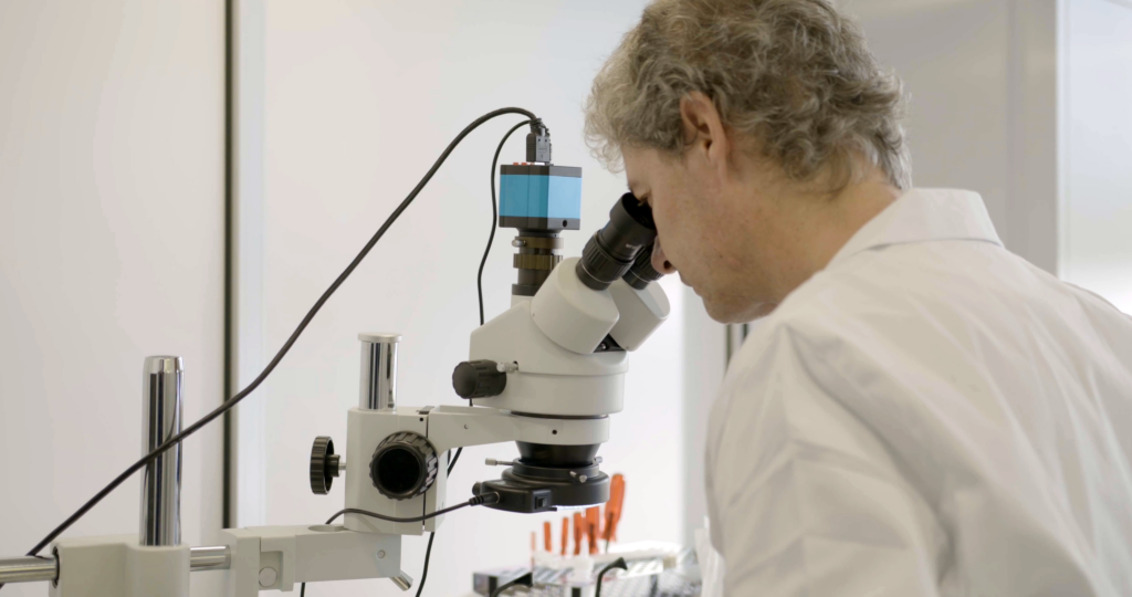 Precision sensor inspection at MC-monitoring's Givisiez facility, Switzerland MC-monitoring engineer inspecting sensor components under a microscope in the Givisiez facility, Switzerland